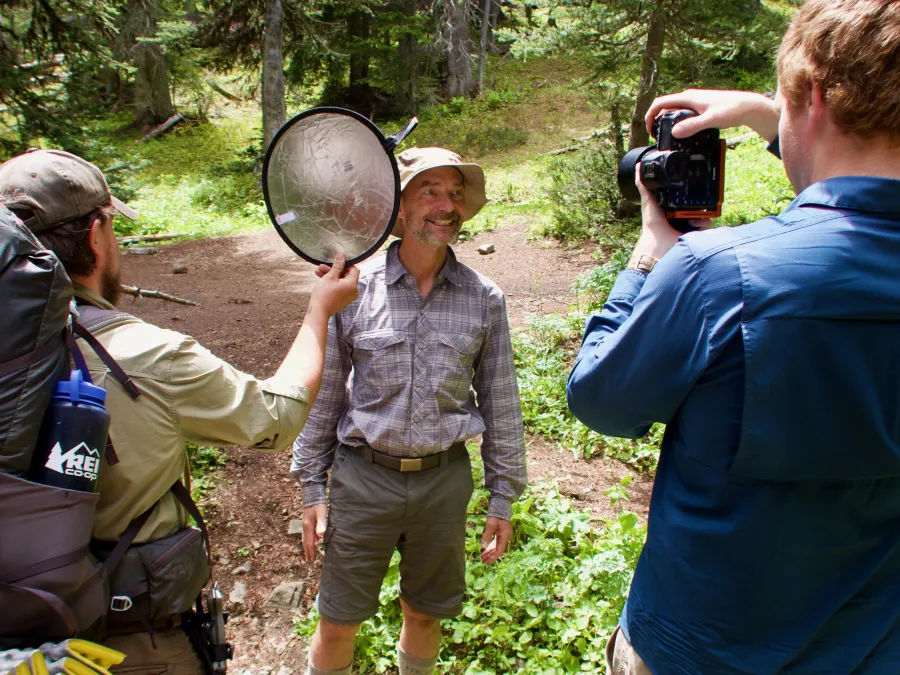 Blue takes a photo of Ralph while K Bar holds a reflector