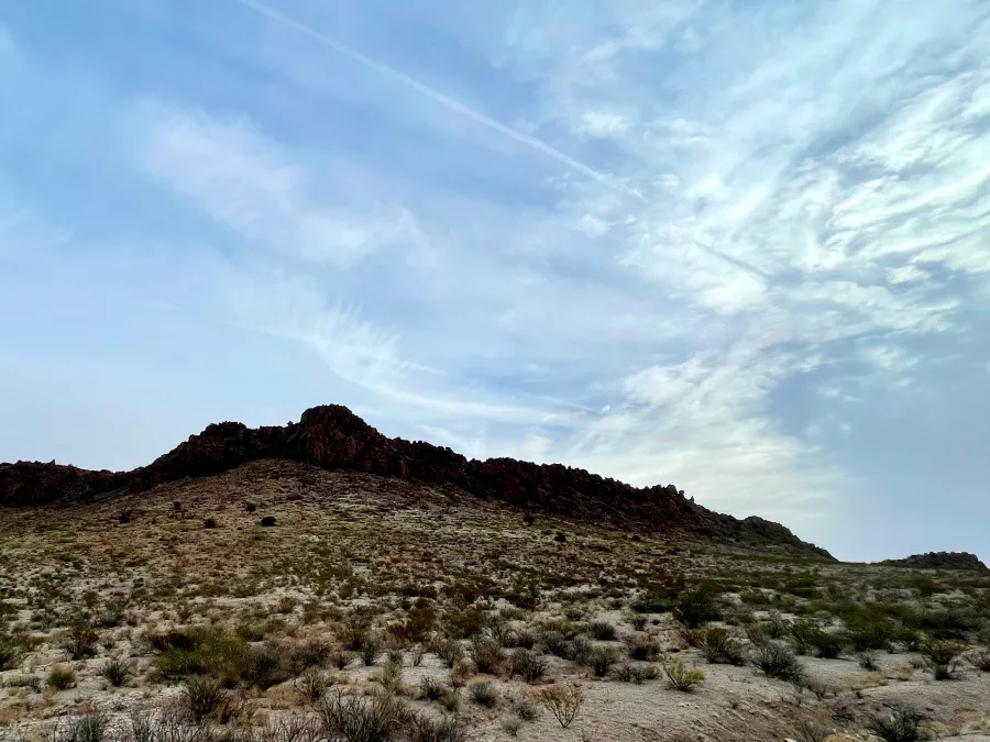Thin clouds hang over a rocky hill