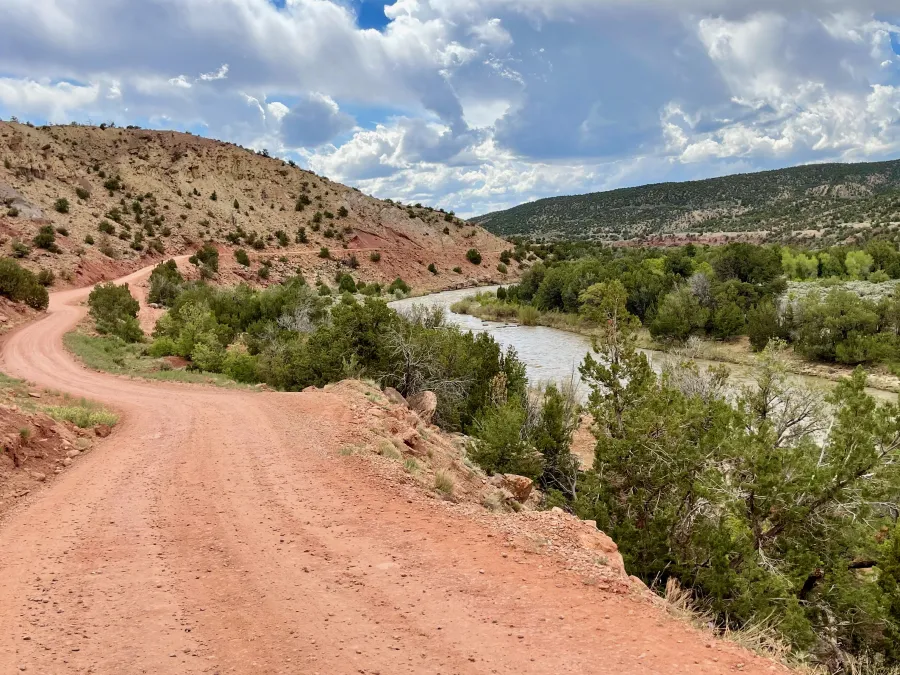 A gravel road follows the Rio Chama