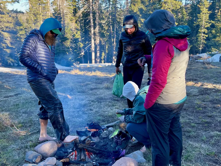 Hikers trying to get warm by a smokey fire