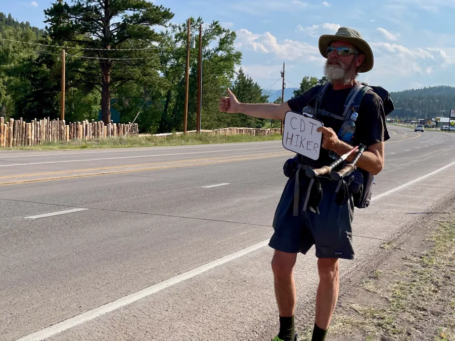Top O' holds a sign while trying to hitchhike