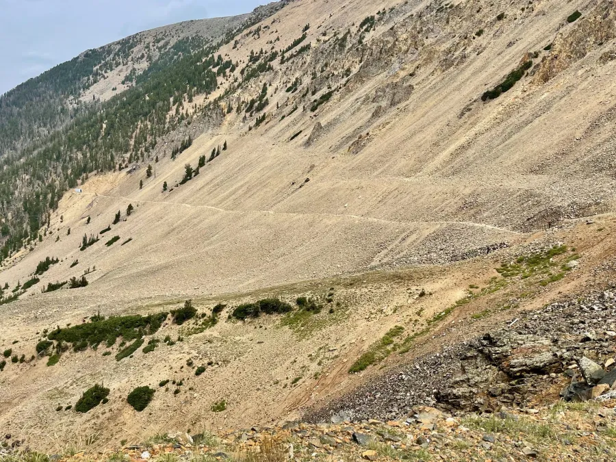 The trail descends across a broad slope of loose rocks and gravel