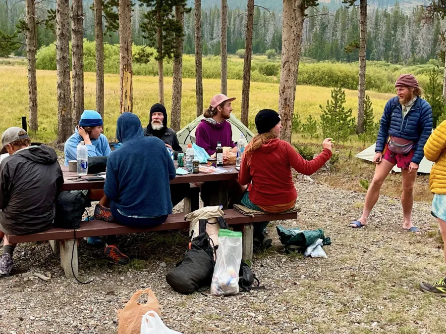 Hikers sit and talk around a picnic table in Lowland Campground