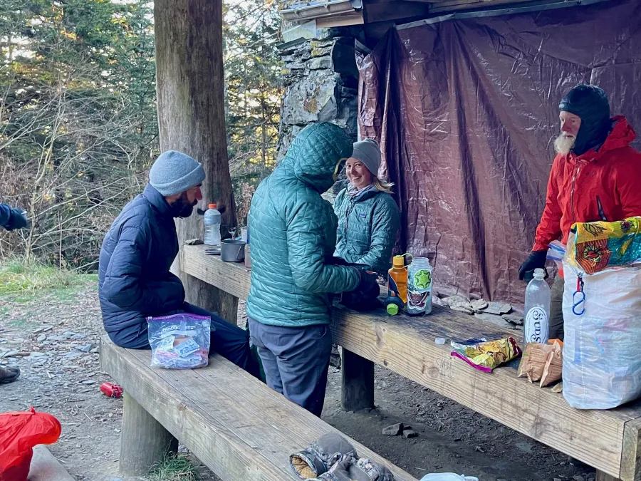 Hikers sitting around a table at Tricorner Knob Shelter