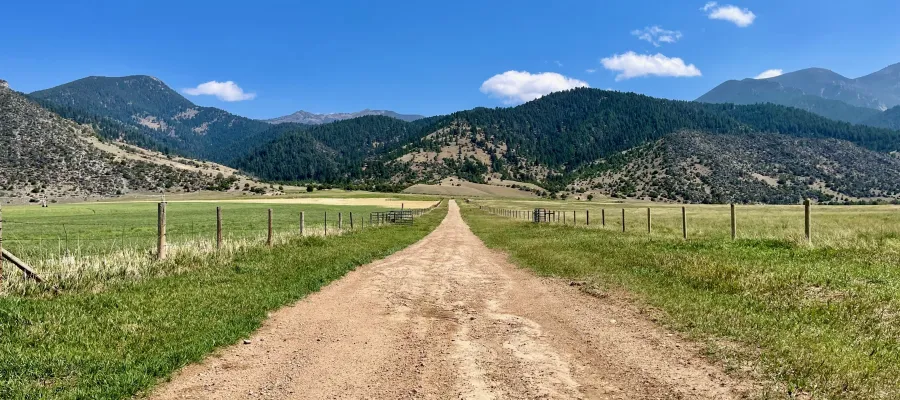 A straight gravel road leads to a mountain range