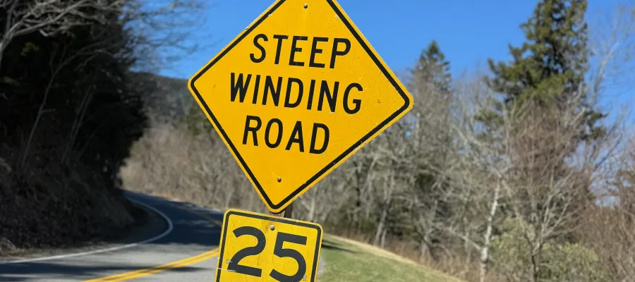 A highway sign says STEEP WINDING ROAD