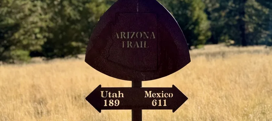 A metal signs points to the souther and northern ends of the Arizona Trail