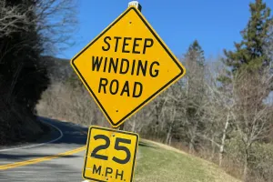A highway sign says STEEP WINDING ROAD