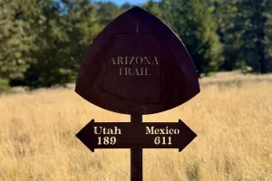 A metal signs points to the souther and northern ends of the Arizona Trail