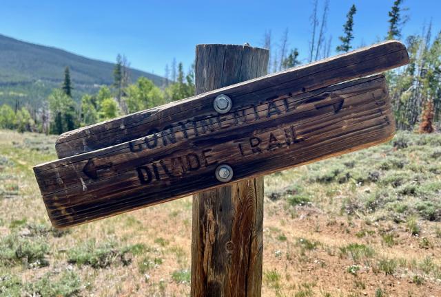 A sign for the trail is mounted crooked on a post