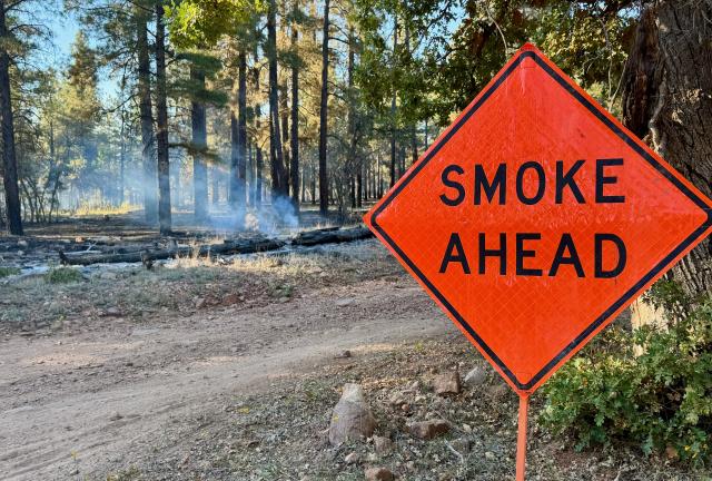 A large road sign warns of smoke ahead